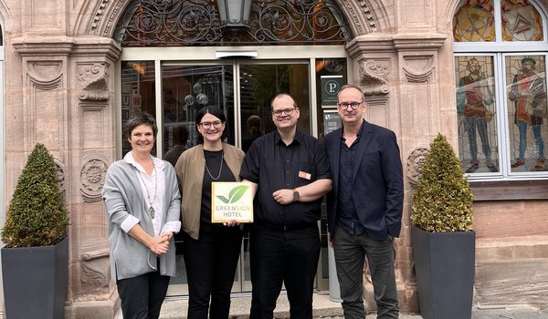 Mitarbeiter präsentieren das GreenSign Zertifikat vor dem Hotel VICTORIA in Nürnberg