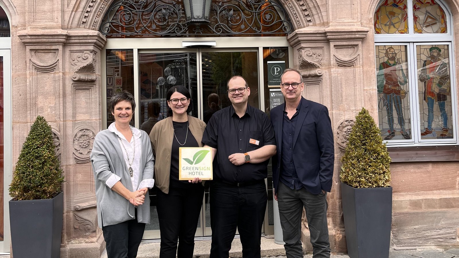 Mitarbeiter präsentieren das GreenSign Zertifikat vor dem Hotel VICTORIA in Nürnberg